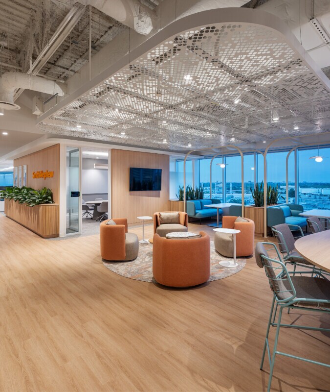 A lounge area at night in an office space with PANEL:form design perforated ceiling panels at Smith Nephew's office