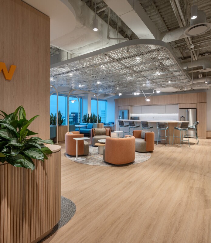A kitchen and lounge area at night with PANEL:form design perforated ceiling panels within Smith Nephew's office