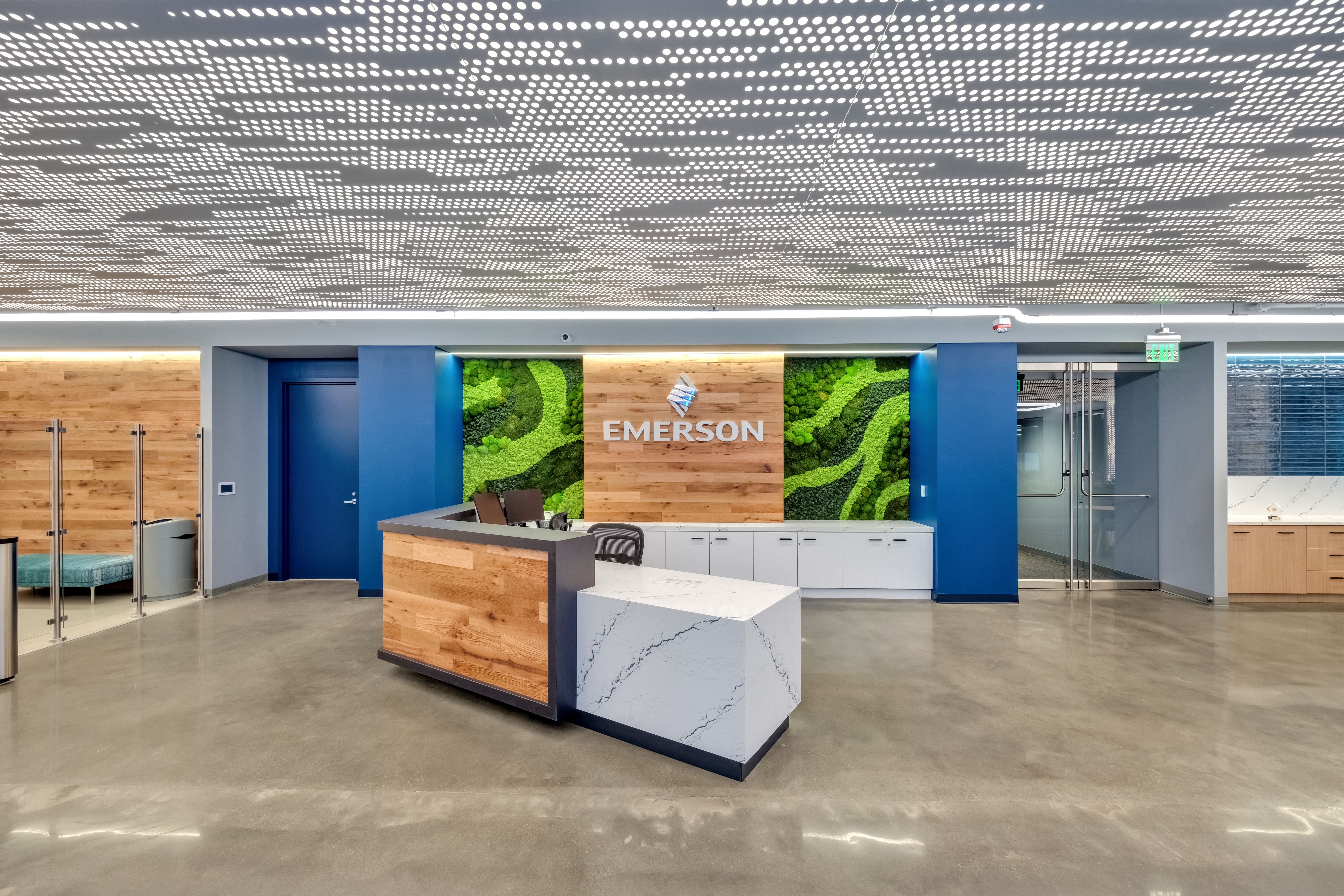 Emerson Electric office reception featuring Agilis backlit perforated wall and ceiling panels with wood accents.