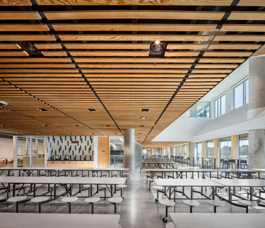 Public tables for students' at the school’s interior, the ceiling uses a custom wood LINE:Form Linear Planks system from Maxxit.