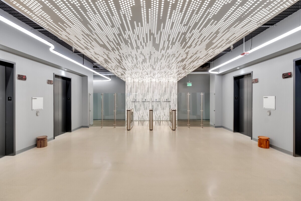 Emerson Electric lobby featuring Agilis backlit perforated wall and ceiling panels above security turnstiles.
