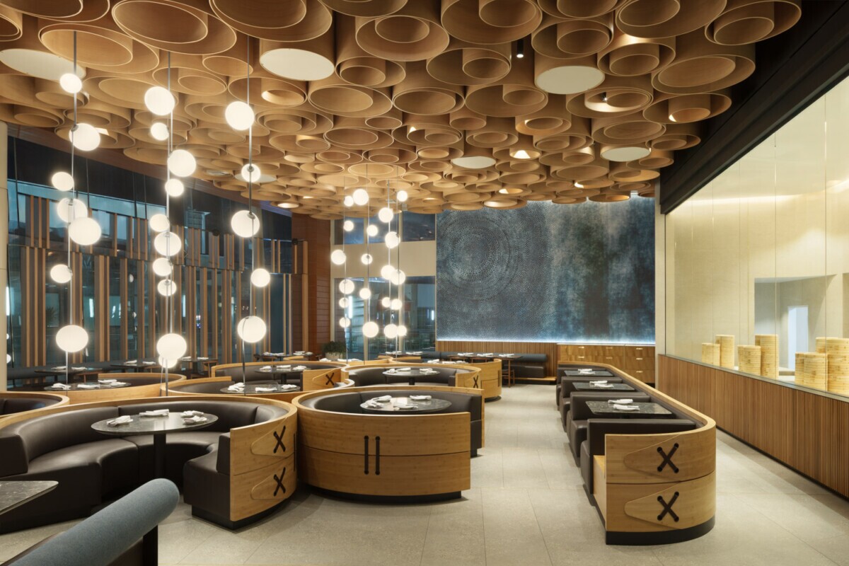View of the interior of Din Tai Fung dining room in Santa Monica, California. Showcasing Maxxit's circular wooden ceiling as well as the wooden partitions to section off the dining room.
